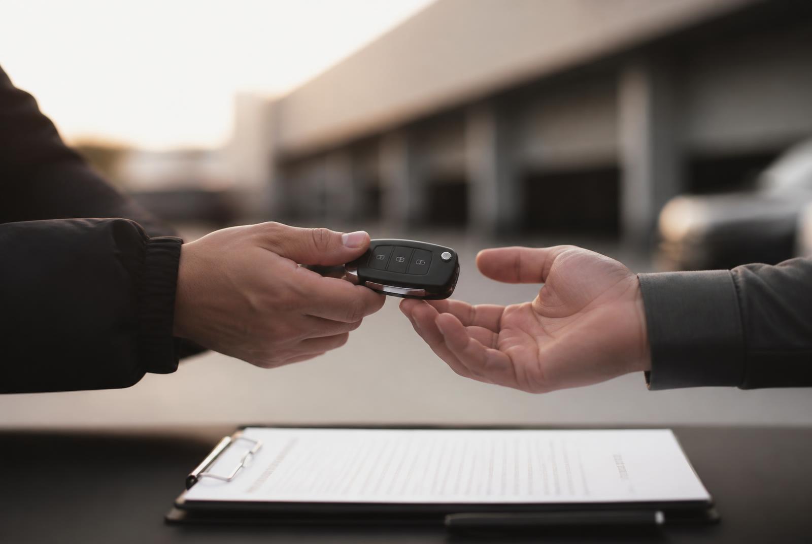 Keys and paperwork changing hands at a dealership during vehicle handoff